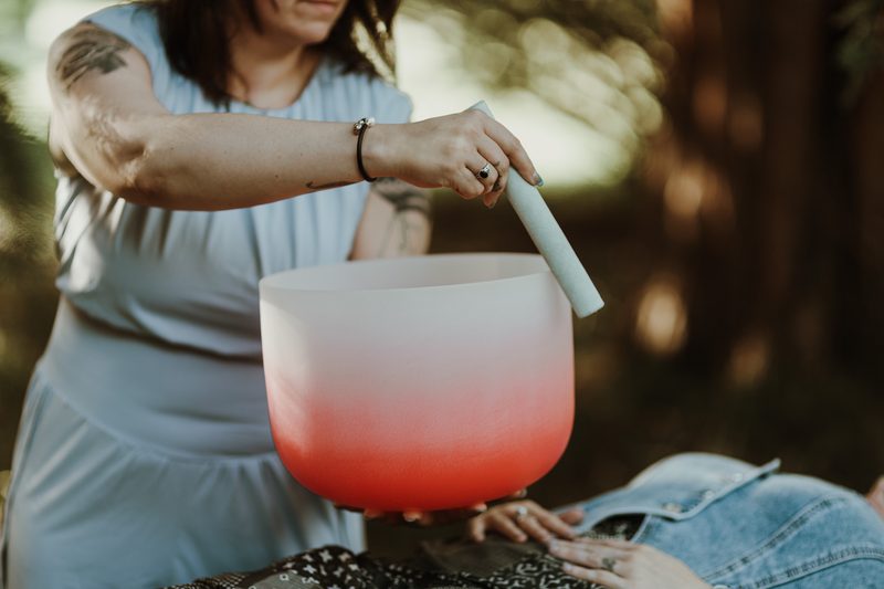A large red crystal singing bowl held and played above a resting client
