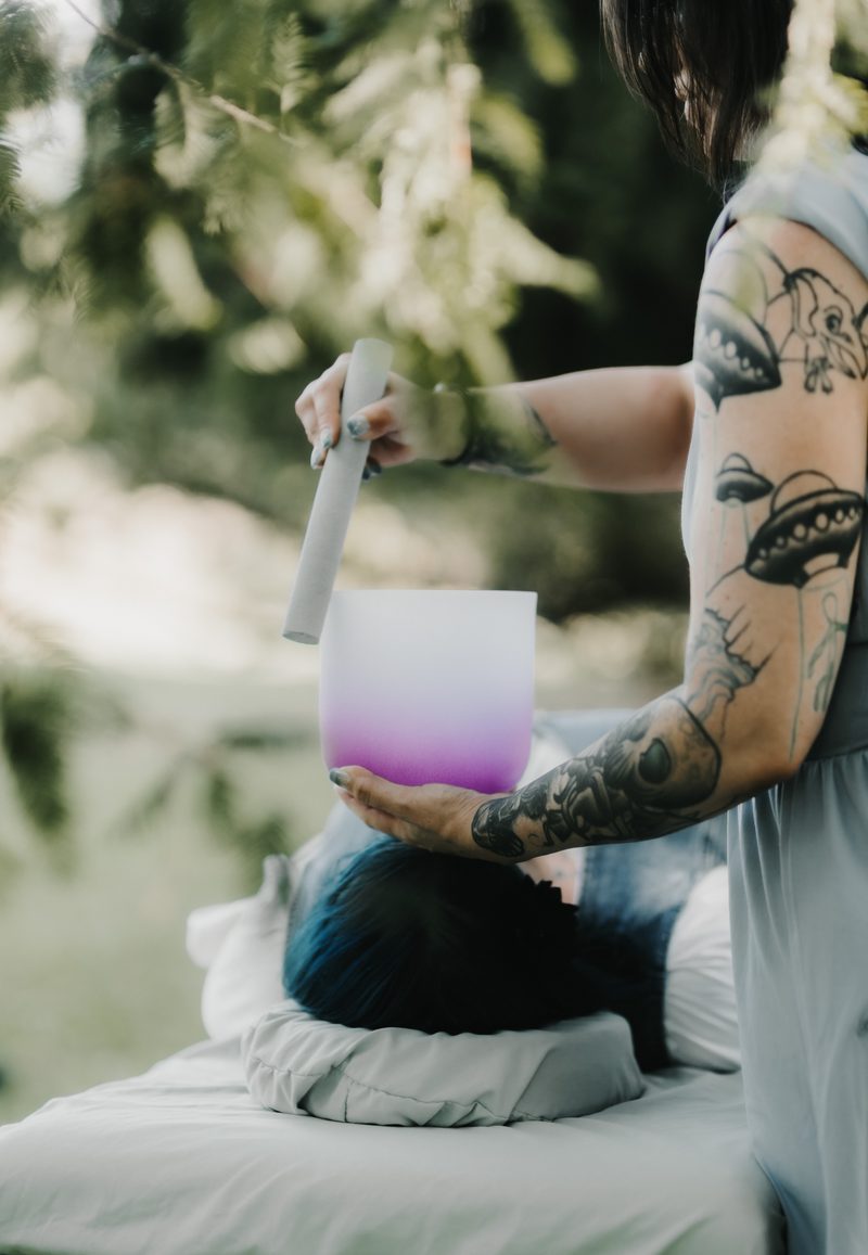 A violet and white crystal singing bowl played just above a reclining client's head